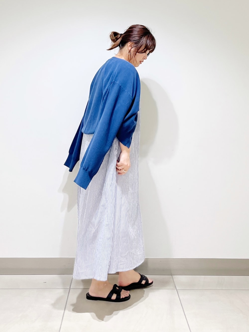 ブルー系のワンピース、ブルー系のニット/セーター、ブラック系のサンダルを着用したレディースの春コーディネートの2枚目の写真