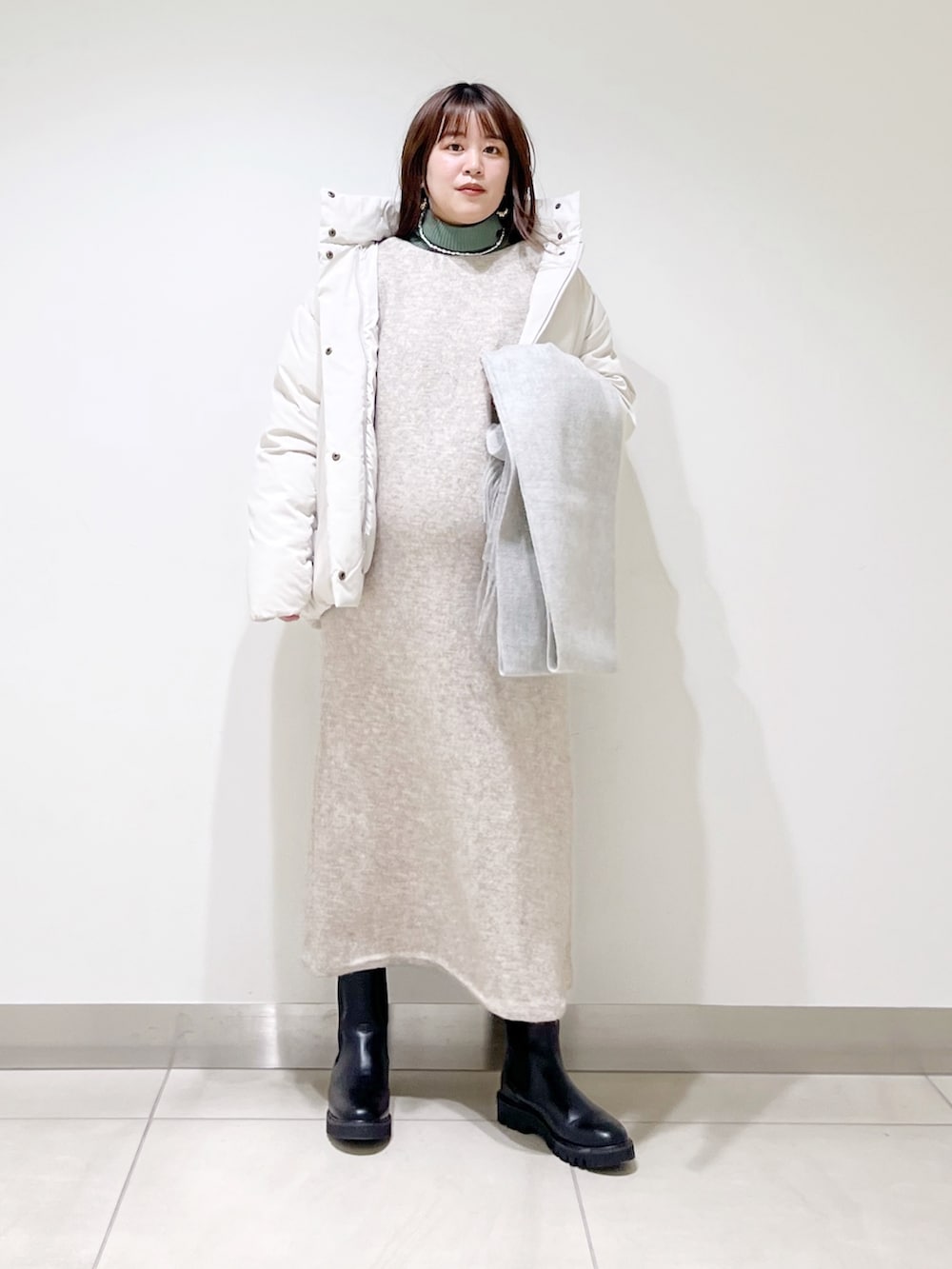 ホワイト系のダウンジャケット/コート、ベージュ系のワンピース、グリーン系のニット/セーターを着用したレディースの冬コーディネートの9枚目の写真