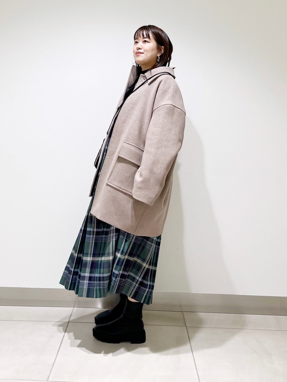 ブラウン系のその他アウター、ブラック系のニット/セーター、グリーン系のスカートを着用したレディースの秋コーディネートの8枚目の写真