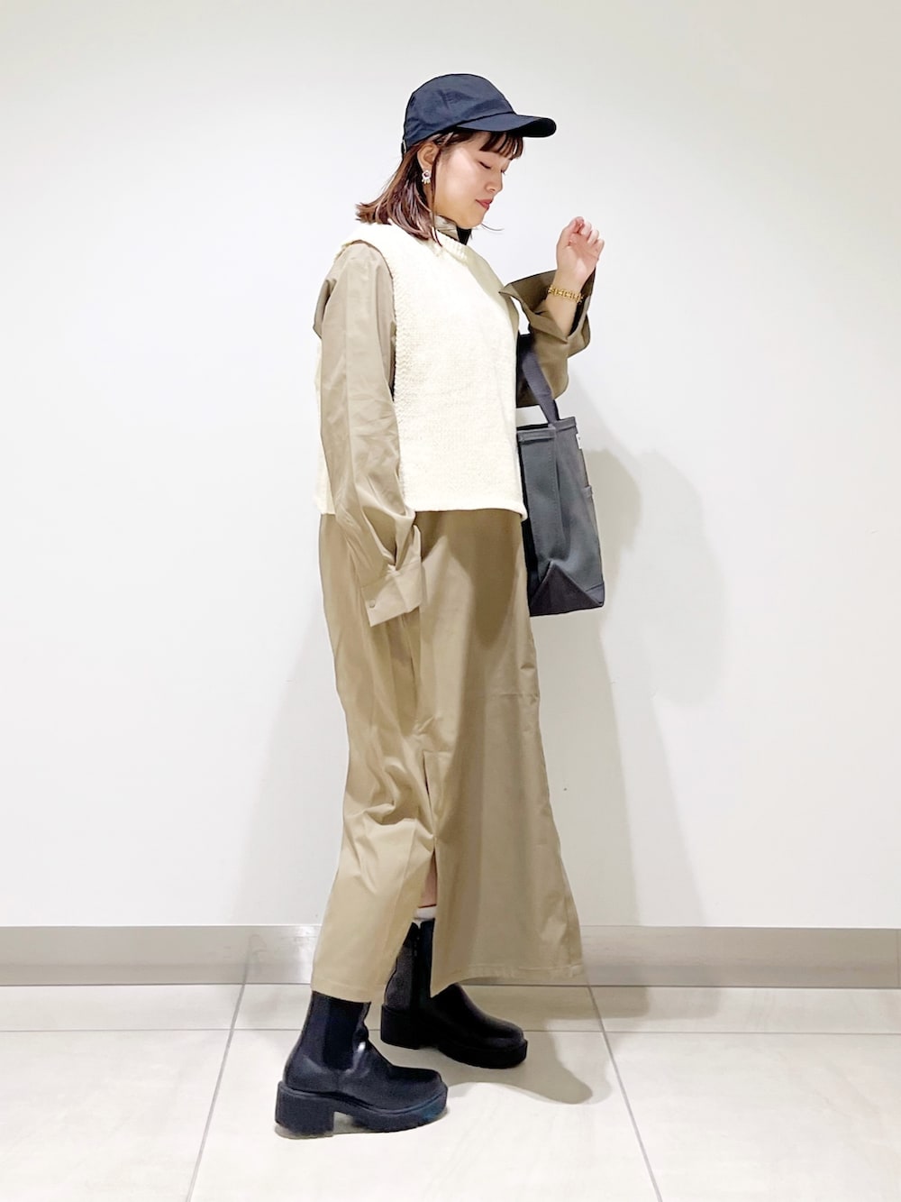 ホワイト系のベスト、グリーン系のワンピース、グレー系のトートバッグを着用したレディースの秋コーディネートの6枚目の写真