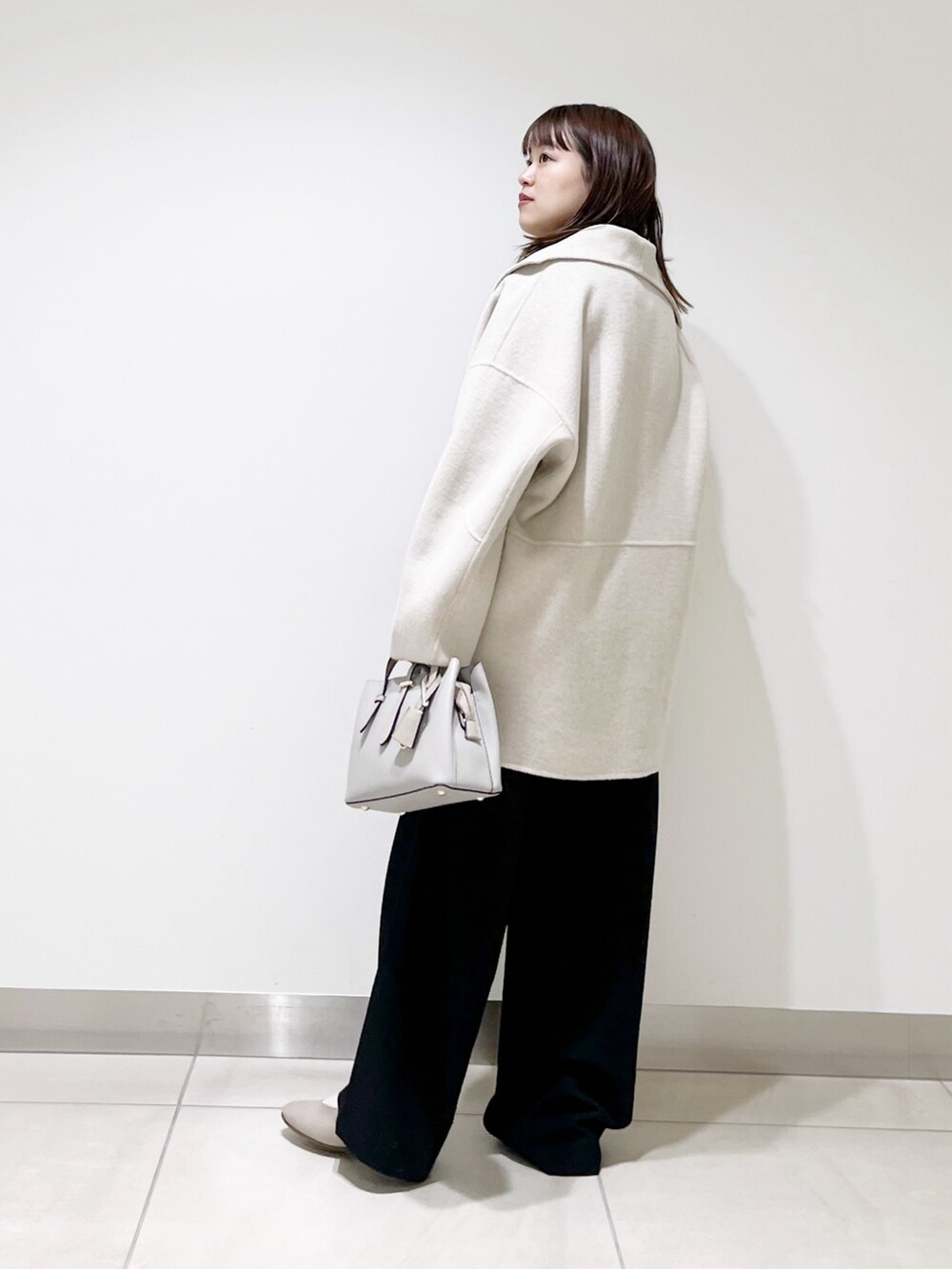 ベージュ系のその他アウター、ブルー系のニット/セーター、ブラック系のパンプスを着用したレディースの冬コーディネートの3枚目の写真