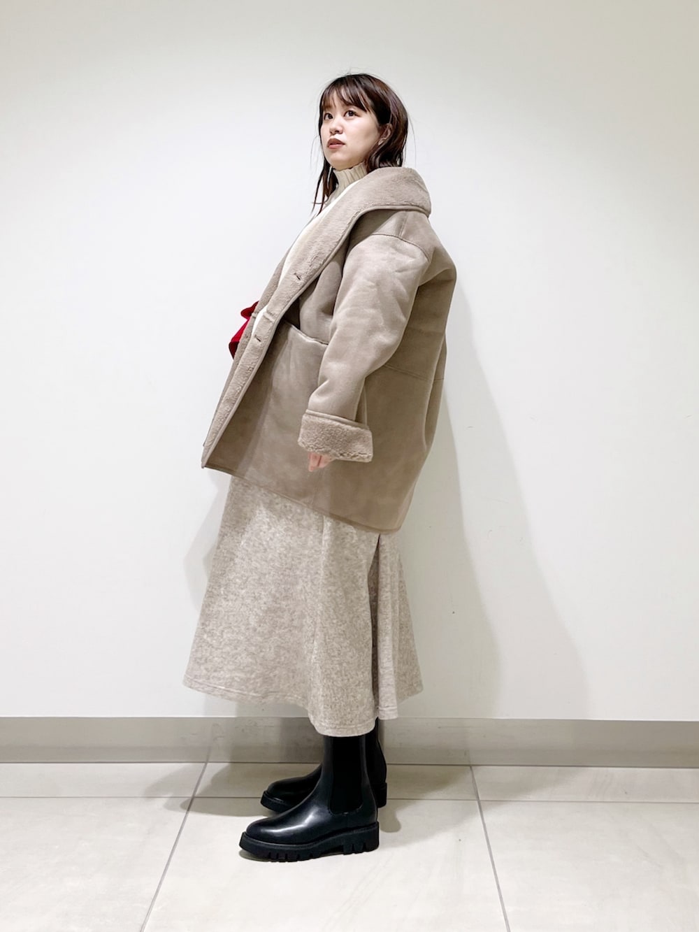 グレー系のムートンコート、ホワイト系のニット/セーター、ベージュ系のスカートを着用したレディースの冬コーディネートの10枚目の写真