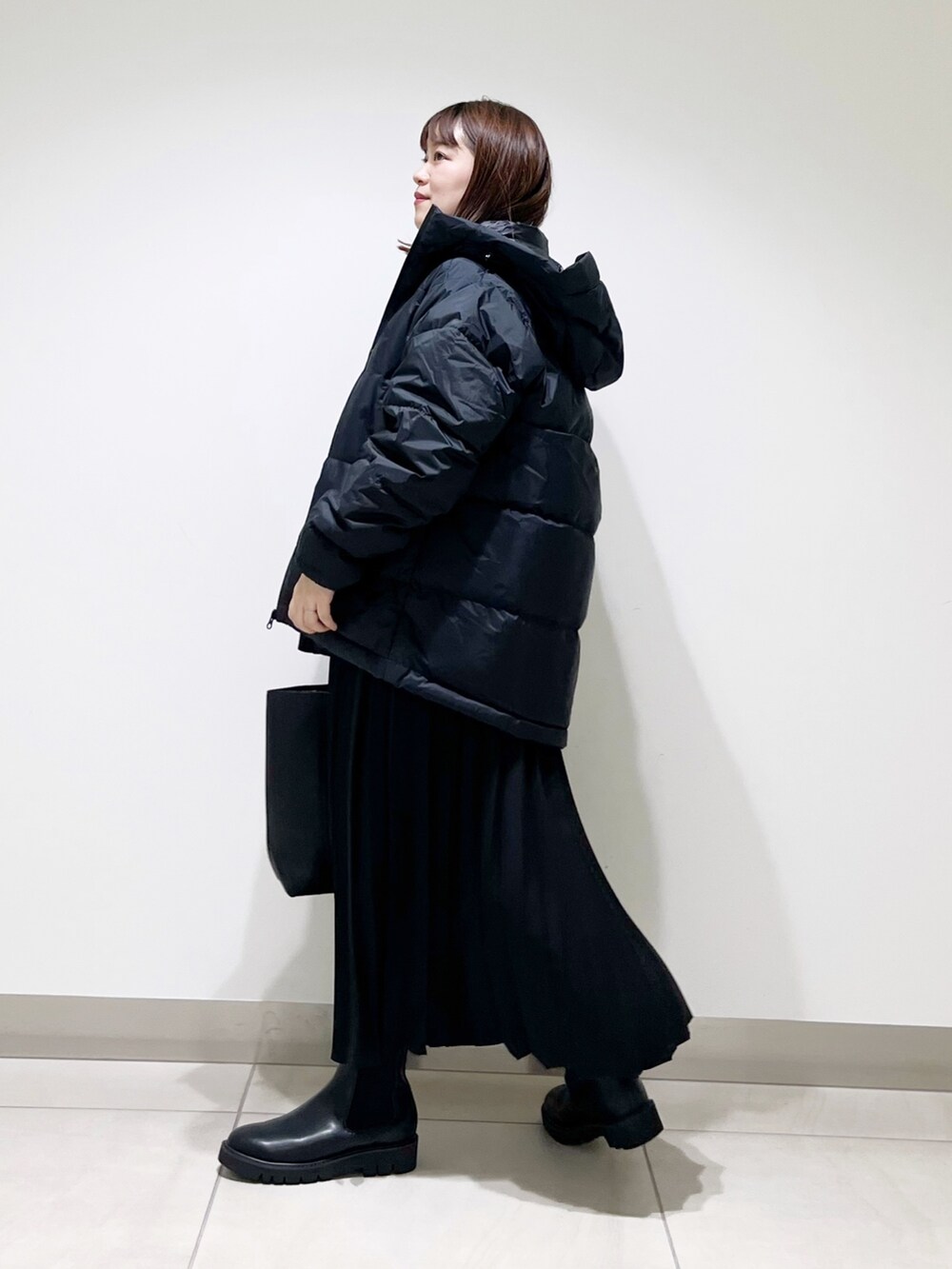 ブラック系のダウンジャケット/コート、ブルー系のTシャツ/カットソー、ブラック系のスカートを着用したレディースの秋コーディネートの5枚目の写真