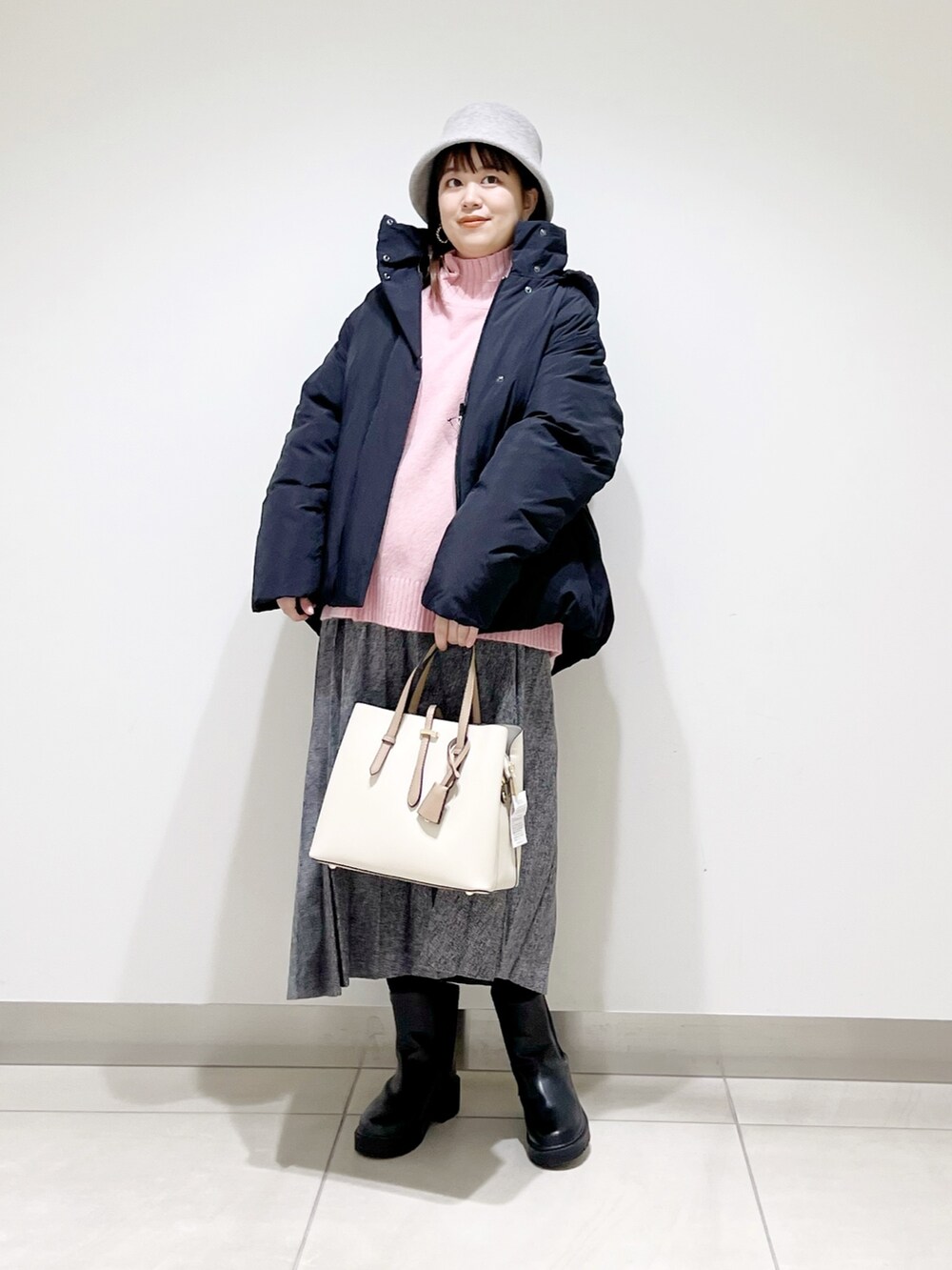 ブラック系のダウンジャケット/コート、ピンク系のニット/セーター、ブルー系のスカートを着用したレディースの冬コーディネートの9枚目の写真