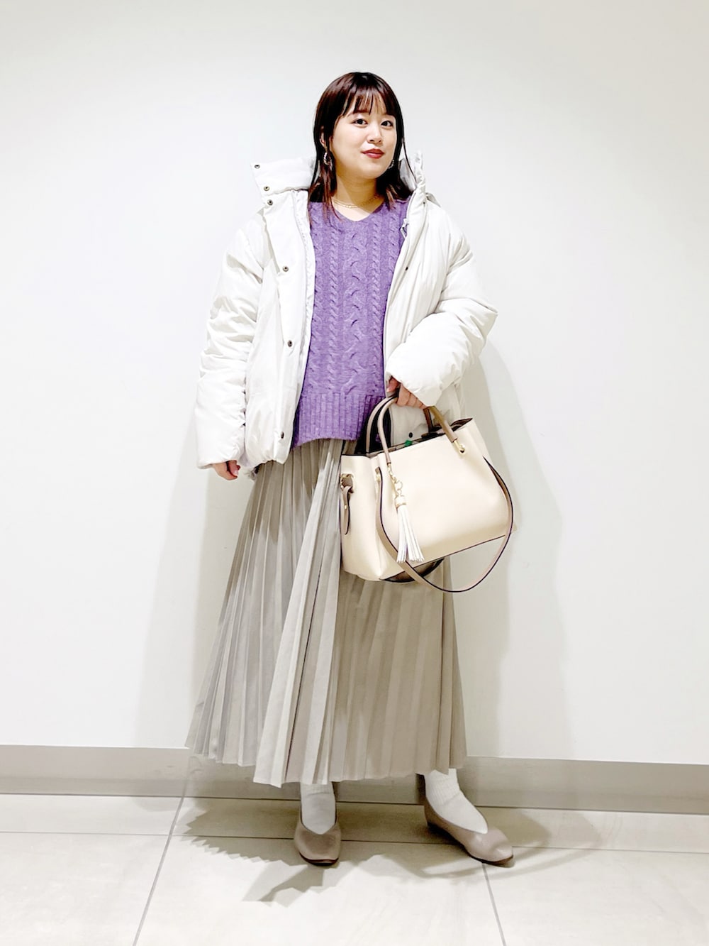 ホワイト系のダウンジャケット/コート、パープル系のニット/セーター、ベージュ系のスカートを着用したレディースの冬コーディネートの3枚目の写真