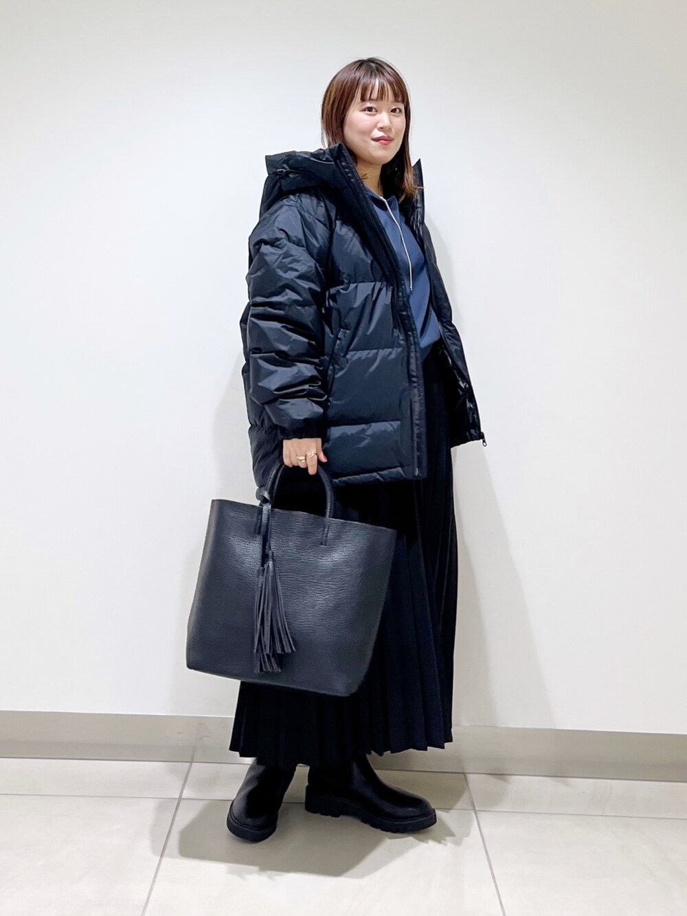 ブラック系のダウンジャケット/コート、ブルー系のTシャツ/カットソー、ブラック系のスカートを着用したレディースの秋コーディネートの9枚目の写真