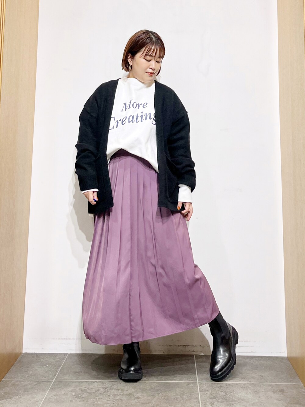 ホワイト系のTシャツ/カットソー、ブラック系のカーディガン/ボレロ、パープル系のスカートを着用したレディースの秋コーディネートの3枚目の写真