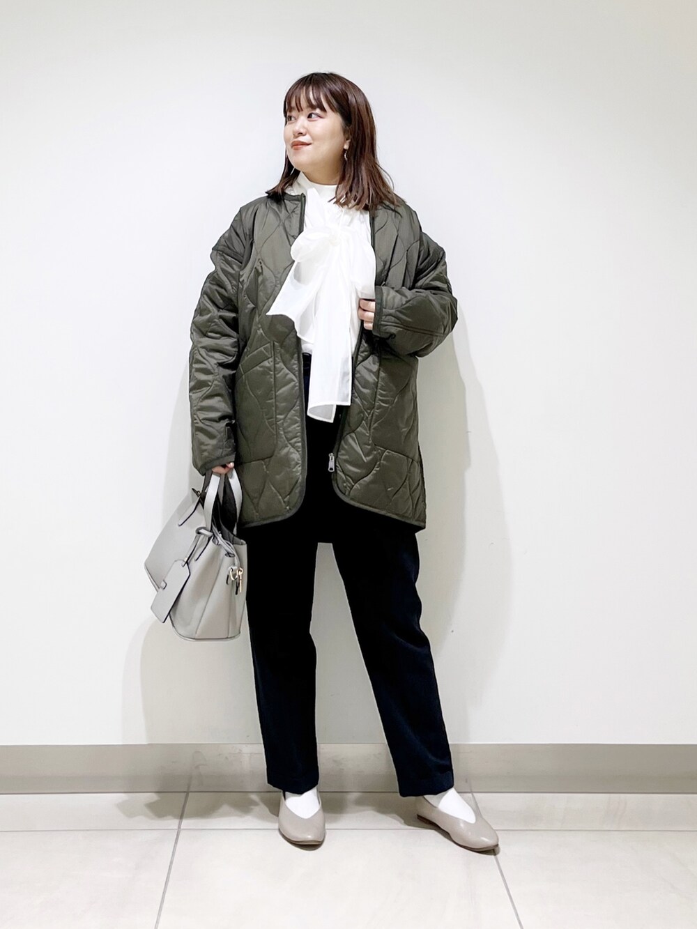 グリーン系のダウンジャケット/コート、ブルー系のパンツ、グレー系のトートバッグを着用したレディースの秋コーディネートの8枚目の写真