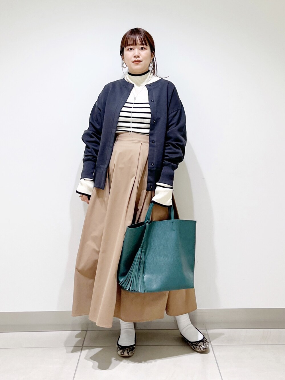 グリーン系のトートバッグ、ベージュ系のスカート、その他のバレエシューズを着用したレディースの秋コーディネートの2枚目の写真