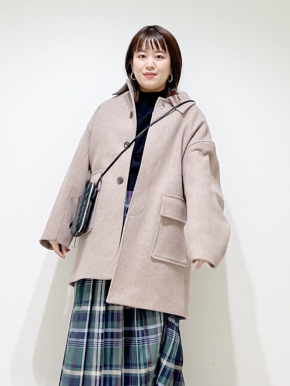 ブラウン系のその他アウター、ブラック系のニット/セーター、グリーン系のスカートを着用したレディースの秋コーディネートの3枚目の写真