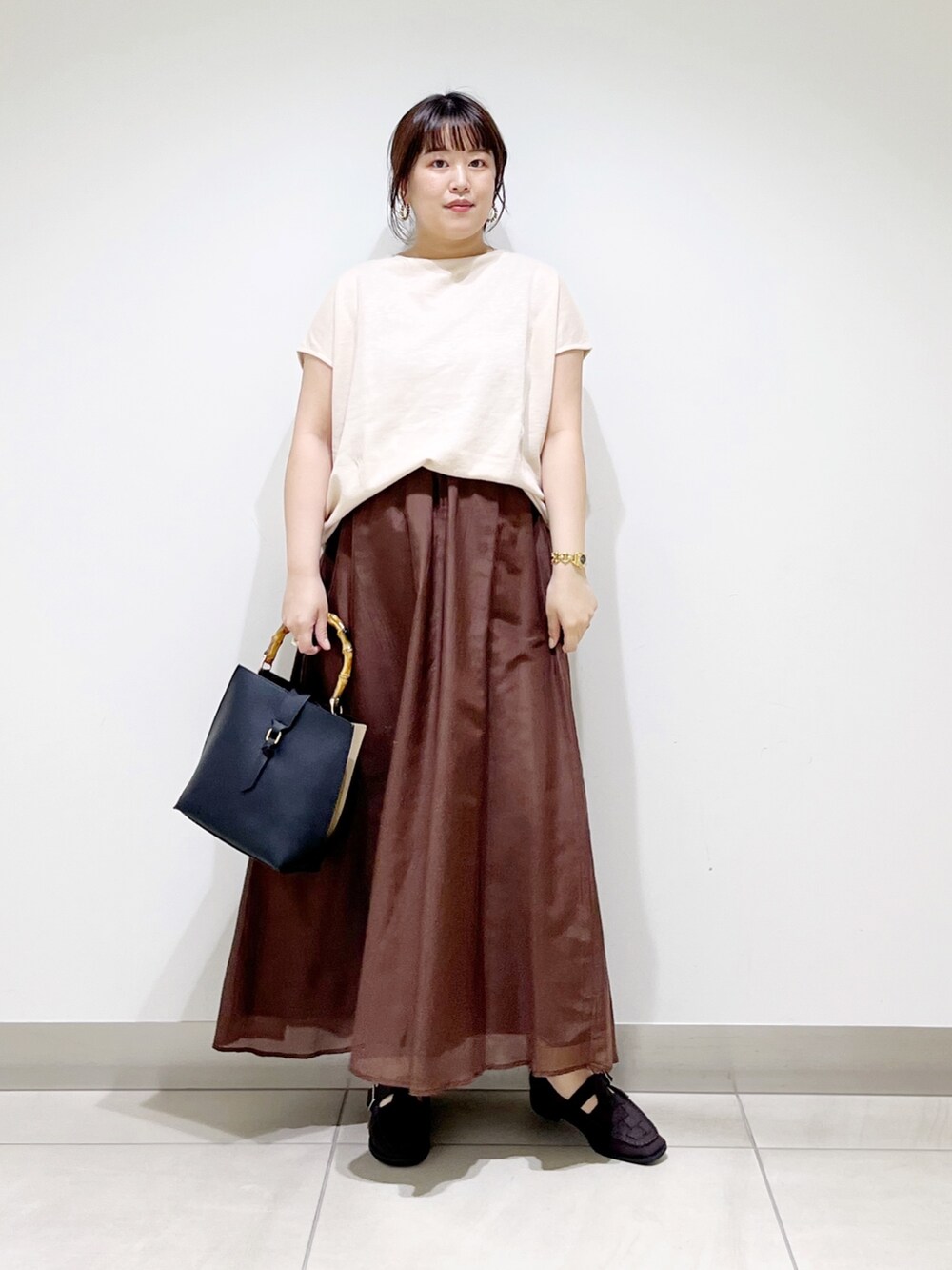 ベージュ系のTシャツ/カットソー、ブラウン系のスカート、ブラック系のハンドバッグを着用したレディースの夏コーディネートの8枚目の写真