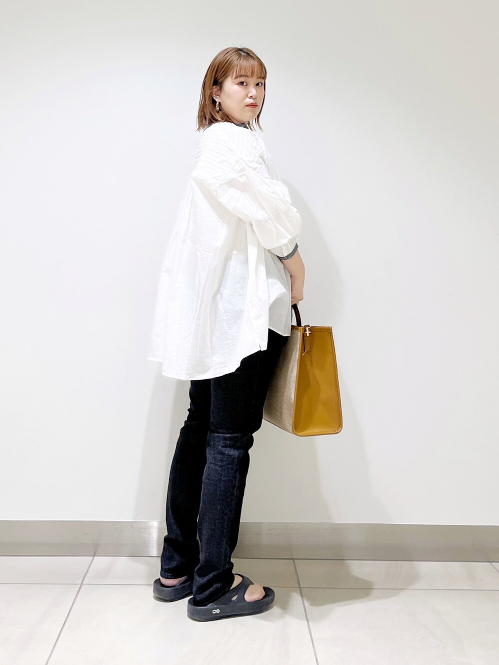 ホワイト系のシャツ/ブラウス、イエロー系のトートバッグ、ブラック系のデニムパンツを着用したレディースの春コーディネートの3枚目の写真