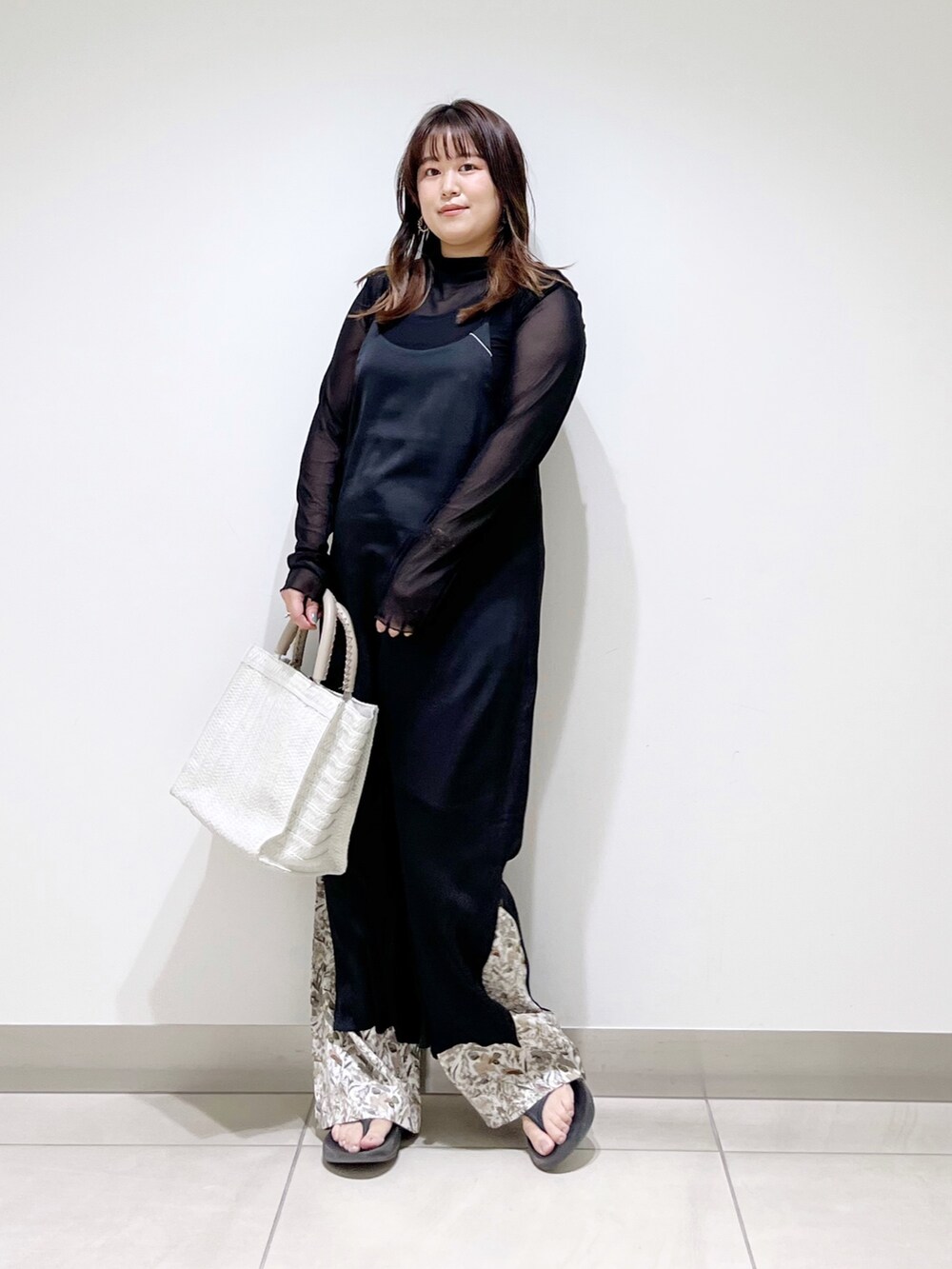 ブラック系のワンピース、ホワイト系のバッグ、ホワイト系のその他パンツを着用したレディースの春コーディネートの2枚目の写真