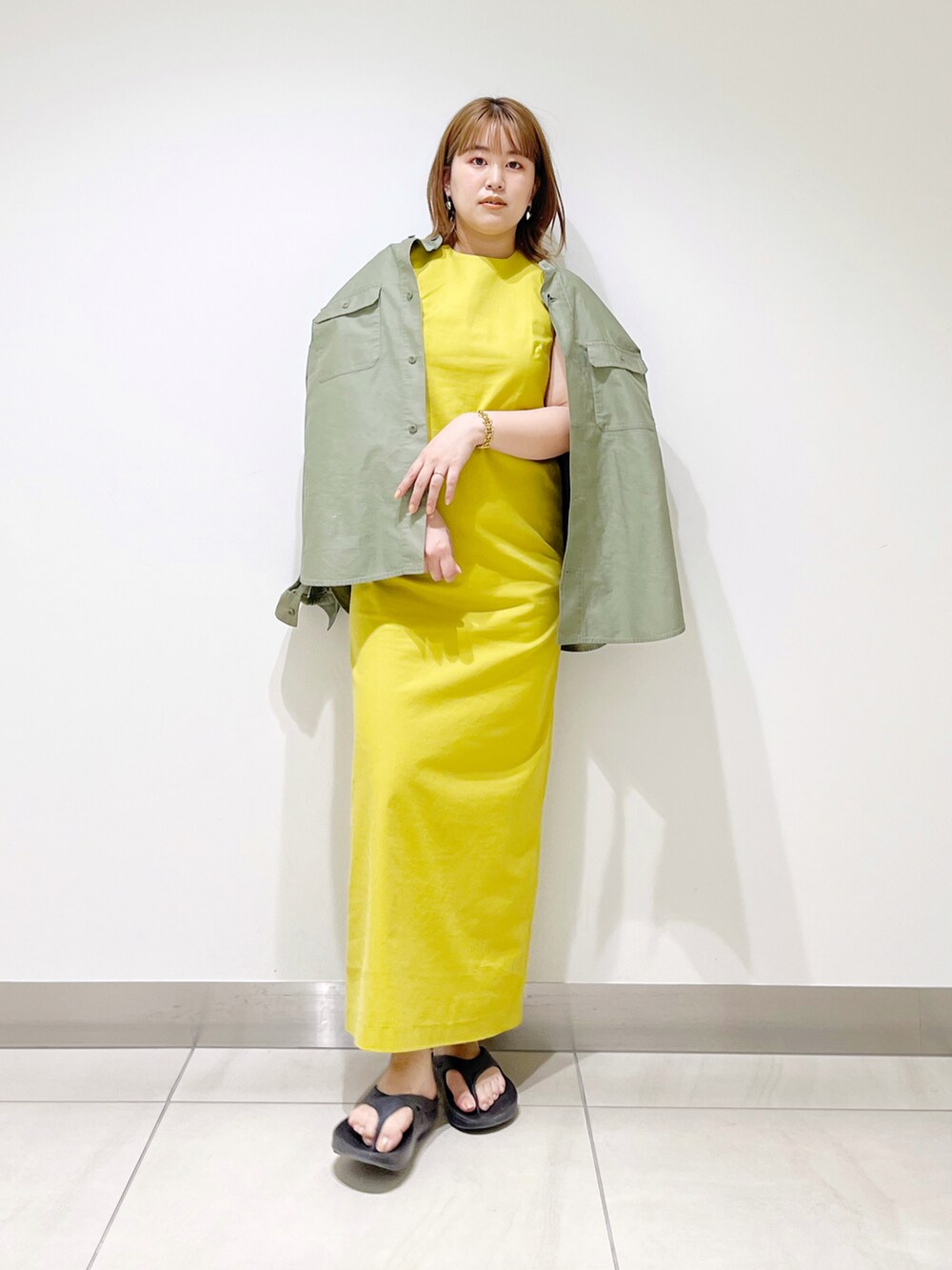 イエロー系のワンピース、グリーン系のシャツ/ブラウス、ブラック系のサンダルを着用したレディースの春コーディネートの4枚目の写真