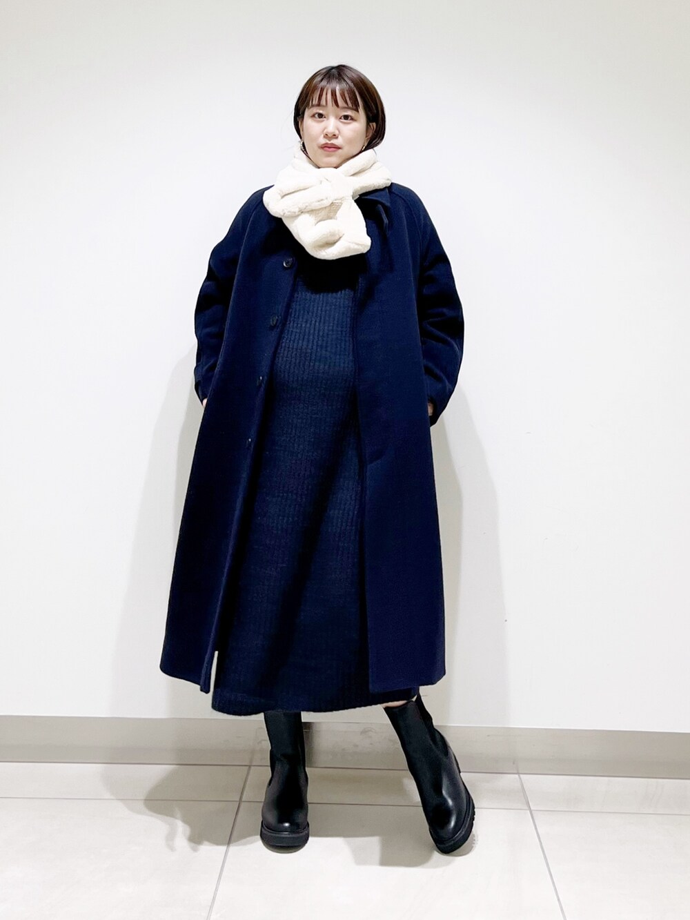 ブルー系のステンカラーコート、ブルー系のワンピース、ブラック系のブーツを着用したレディースの冬コーディネートの8枚目の写真