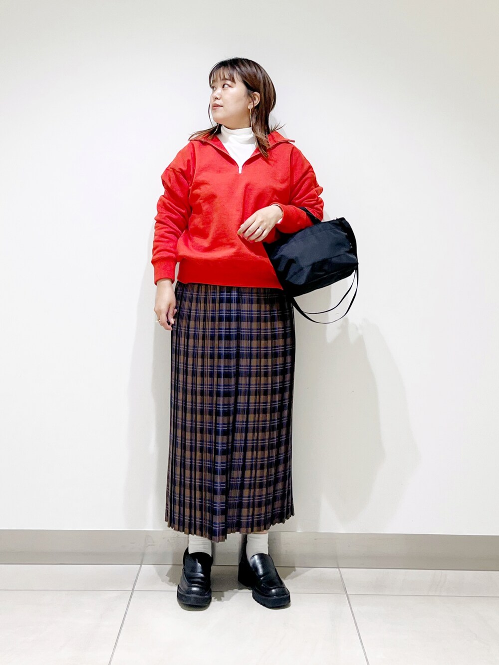 オレンジ系のスウェット、ブルー系のスカート、ブラック系のショルダーバッグを着用したレディースの秋コーディネートの5枚目の写真