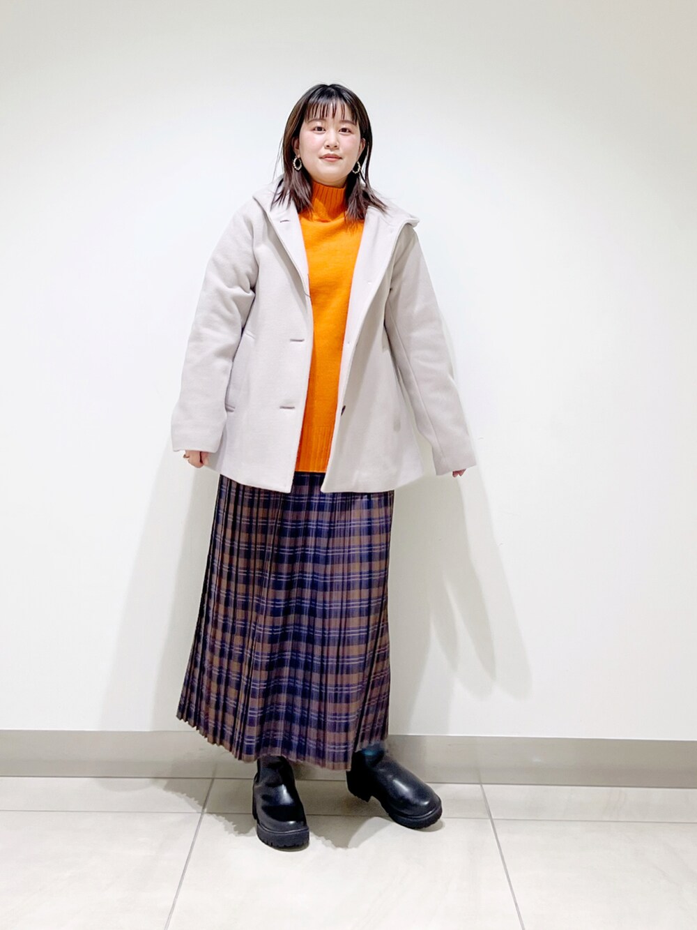 ベージュ系のその他アウター、オレンジ系のニット/セーター、ブルー系のスカートを着用したレディースの秋コーディネートの2枚目の写真