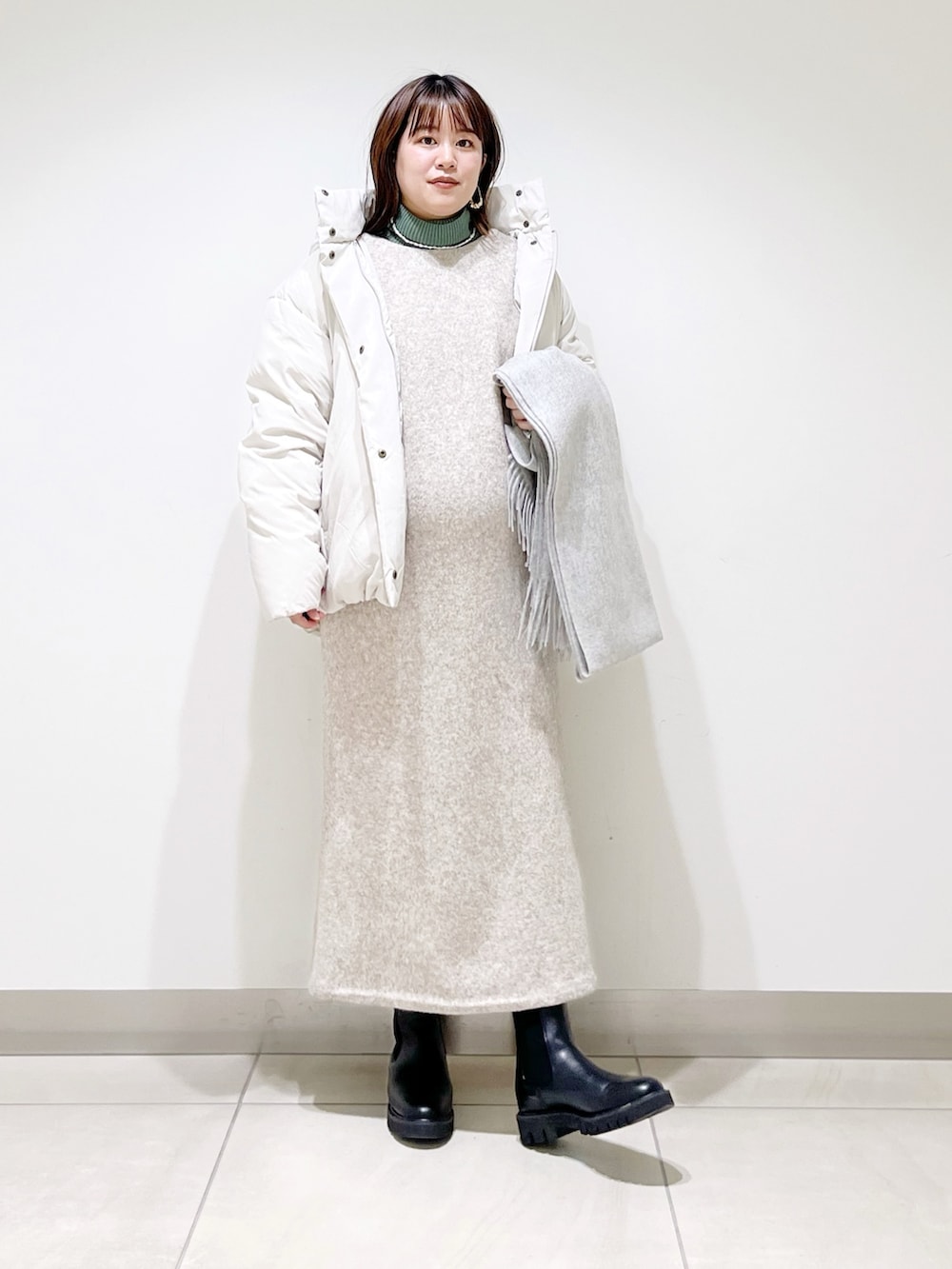 ホワイト系のダウンジャケット/コート、ベージュ系のワンピース、グリーン系のニット/セーターを着用したレディースの冬コーディネートの7枚目の写真