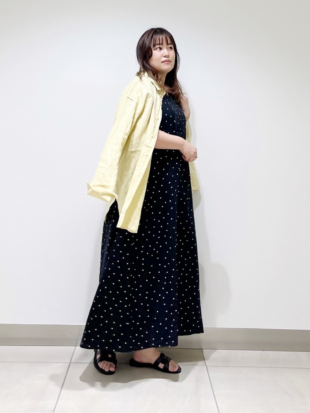 ブラック系のワンピース、イエロー系のシャツ/ブラウス、ブラック系のサンダルを着用したレディースの春コーディネートの4枚目の写真