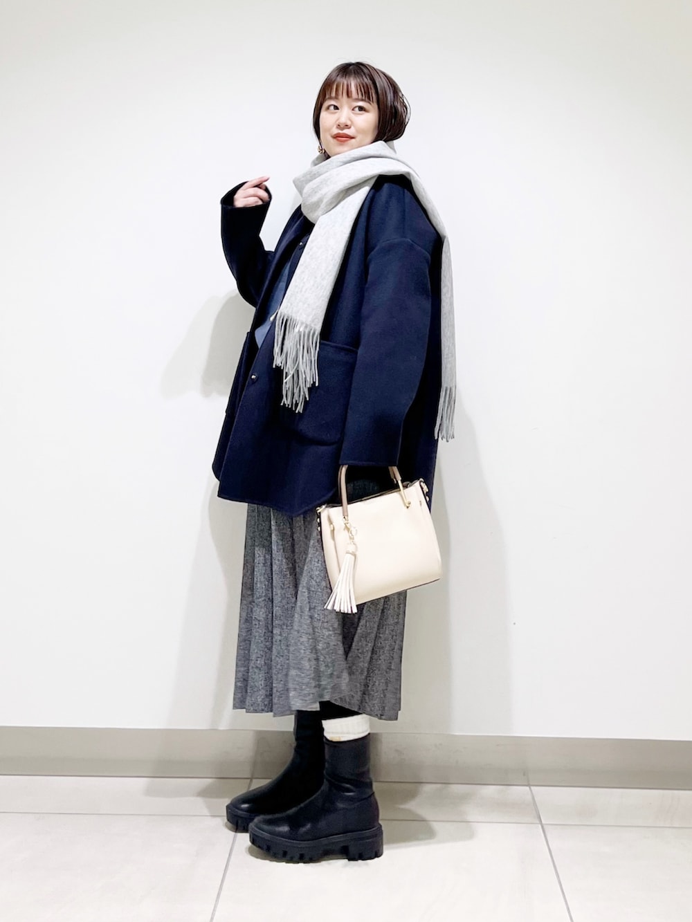 ブルー系のノーカラージャケット、グレー系のニット/セーター、ブルー系のスカートを着用したレディースの秋コーディネートの8枚目の写真