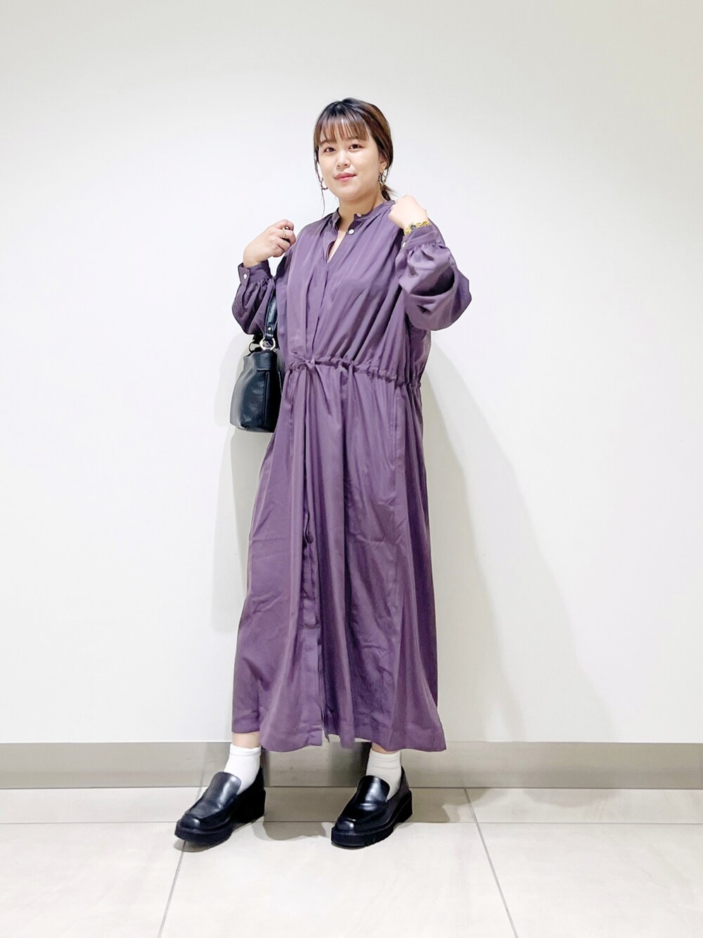 パープル系のワンピース、ブラック系のローファー、ブラック系のハンドバッグを着用したレディースの秋コーディネートの3枚目の写真