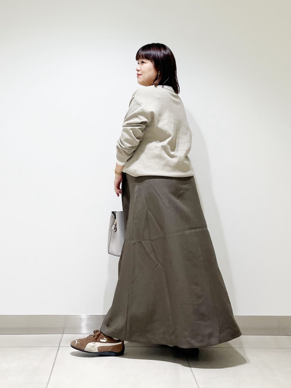 ベージュ系のTシャツ/カットソー、ブラウン系のスカート、グレー系のトートバッグを着用したレディースの秋コーディネートの6枚目の写真