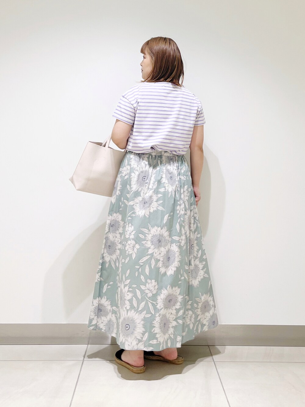 グリーン系のスカート、パープル系のTシャツ/カットソー、ホワイト系のトートバッグを着用したレディースの春コーディネートの4枚目の写真