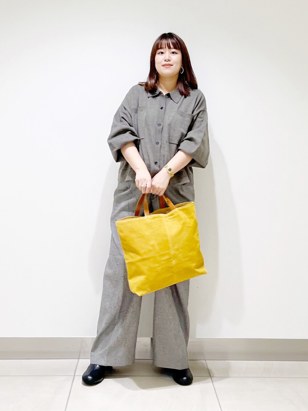 グレー系のニット/セーター、ベージュ系のパンツ、イエロー系のトートバッグを着用したレディースの秋コーディネートの3枚目の写真
