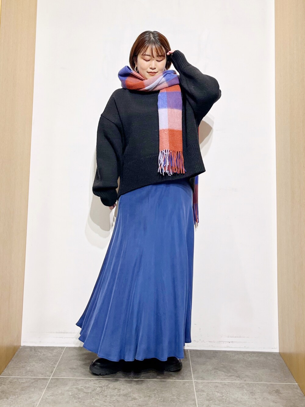 ブラック系のニット/セーター、ブルー系のスカート、ブラック系のブーツを着用したレディースの冬コーディネートの2枚目の写真