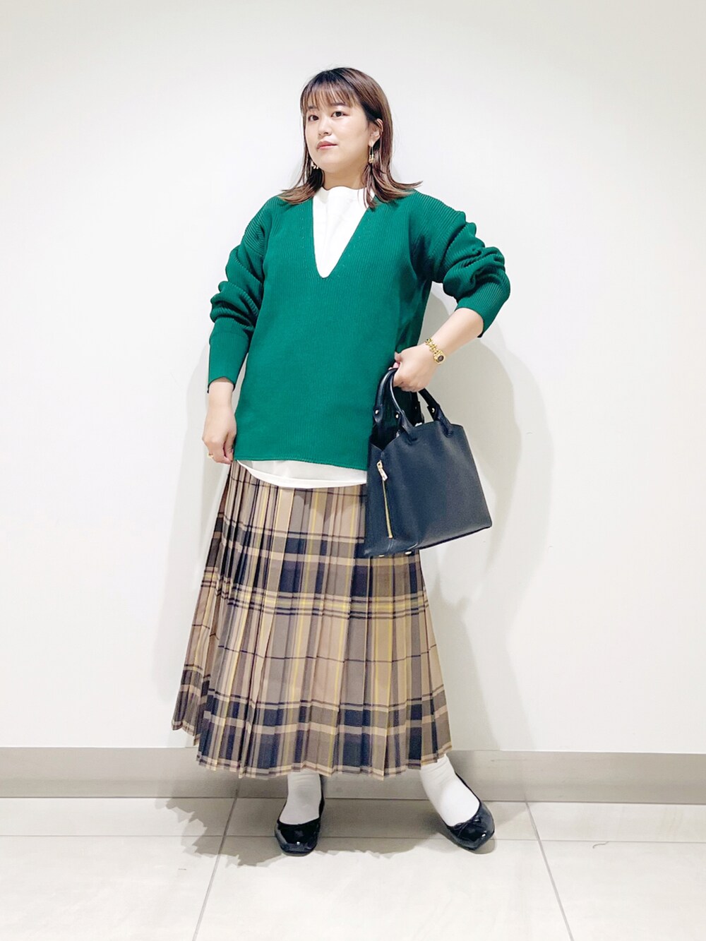 グリーン系のニット/セーター、ブラック系のトートバッグ、ベージュ系のスカートを着用したレディースの秋コーディネートの2枚目の写真