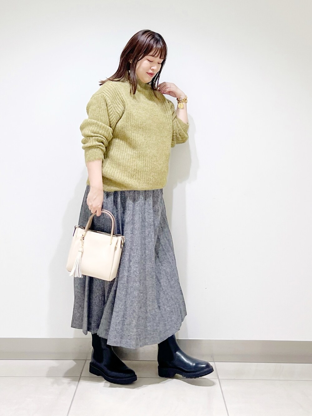 グリーン系のニット/セーター、ブルー系のスカート、ホワイト系のトートバッグを着用したレディースの冬コーディネートの8枚目の写真
