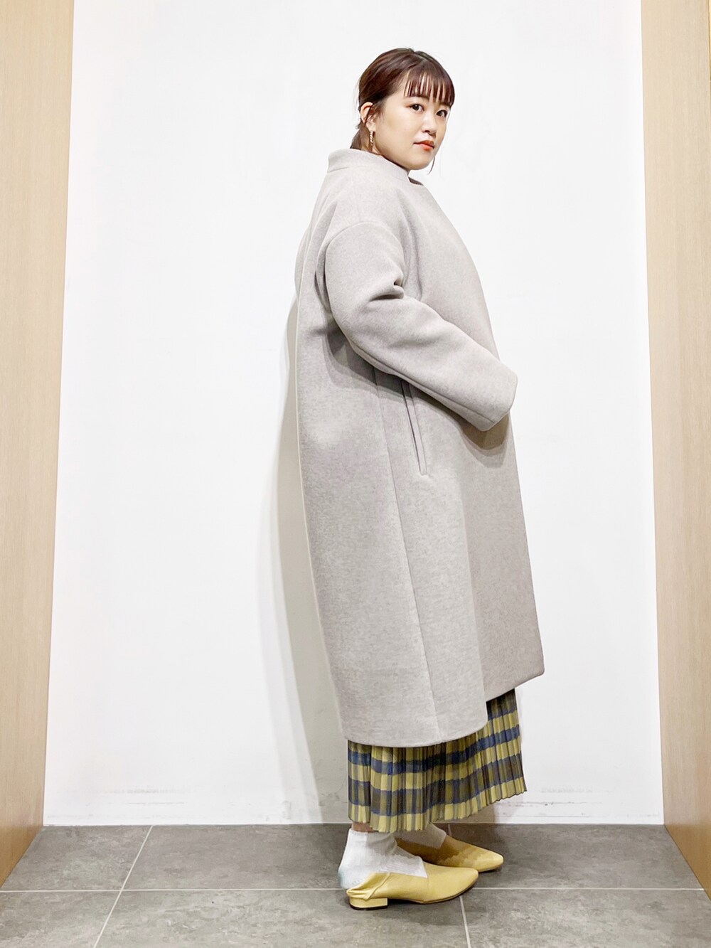 ベージュ系のニット/セーター、グレー系のその他アウター、イエロー系のスカートを着用したレディースの冬コーディネートの3枚目の写真