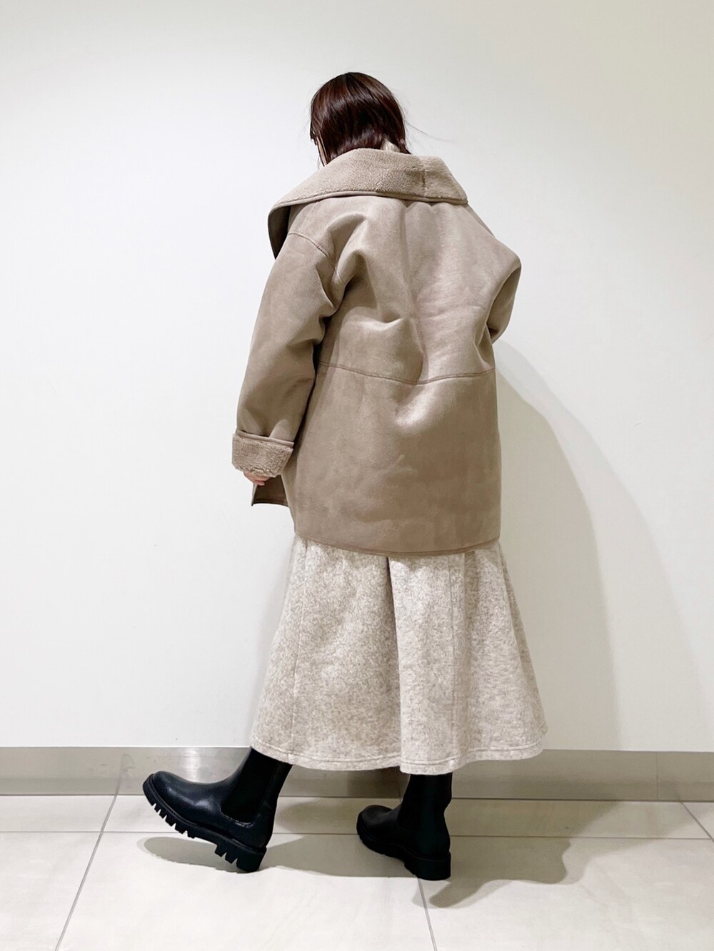 グレー系のムートンコート、ホワイト系のニット/セーター、ベージュ系のスカートを着用したレディースの冬コーディネートの6枚目の写真