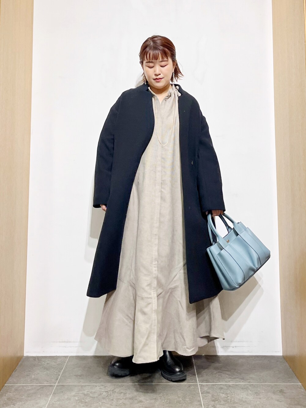 ベージュ系のワンピース、ブラック系のその他アウター、ブルー系のトートバッグを着用したレディースの冬コーディネートの3枚目の写真