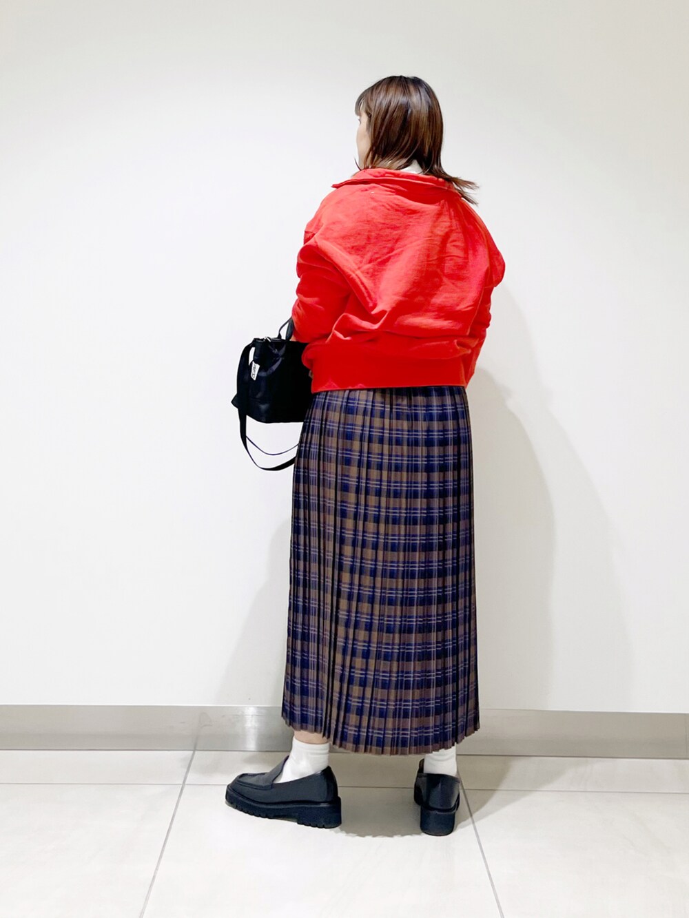 オレンジ系のスウェット、ブルー系のスカート、ブラック系のショルダーバッグを着用したレディースの秋コーディネートの3枚目の写真