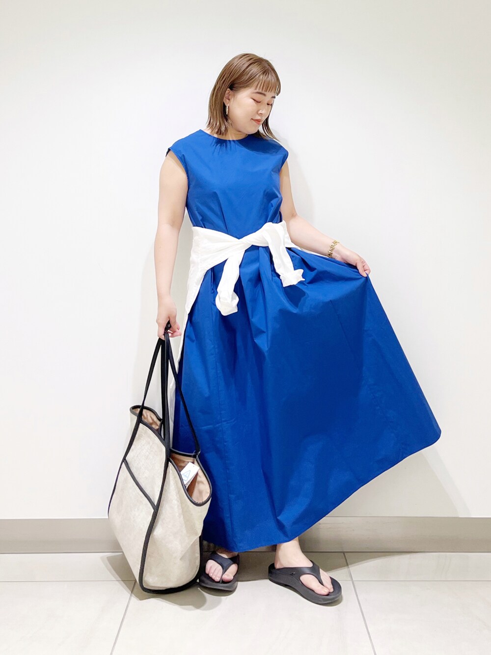 ブルー系のワンピース、ブラック系のトートバッグ、ブラック系のサンダルを着用したレディースの春コーディネートの3枚目の写真