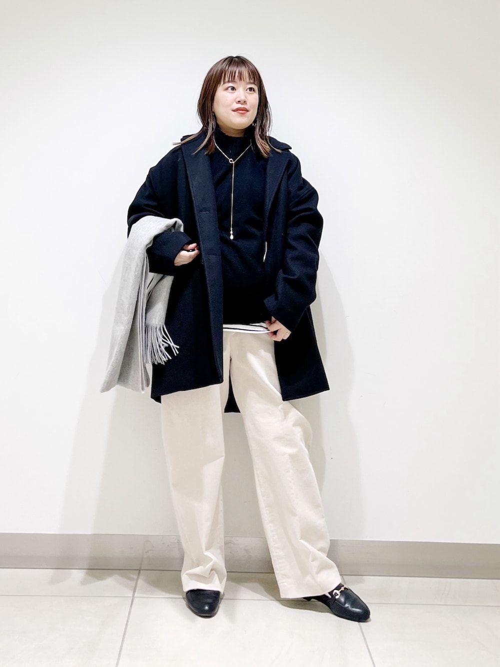 ブルー系のピーコート、ブラック系のニット/セーター、ホワイト系のTシャツ/カットソーを着用したレディースの冬コーディネートの7枚目の写真