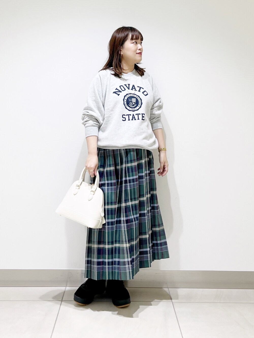 グリーン系のスカート、グレー系のスウェット、ホワイト系のショルダーバッグを着用したレディースの冬コーディネートの10枚目の写真