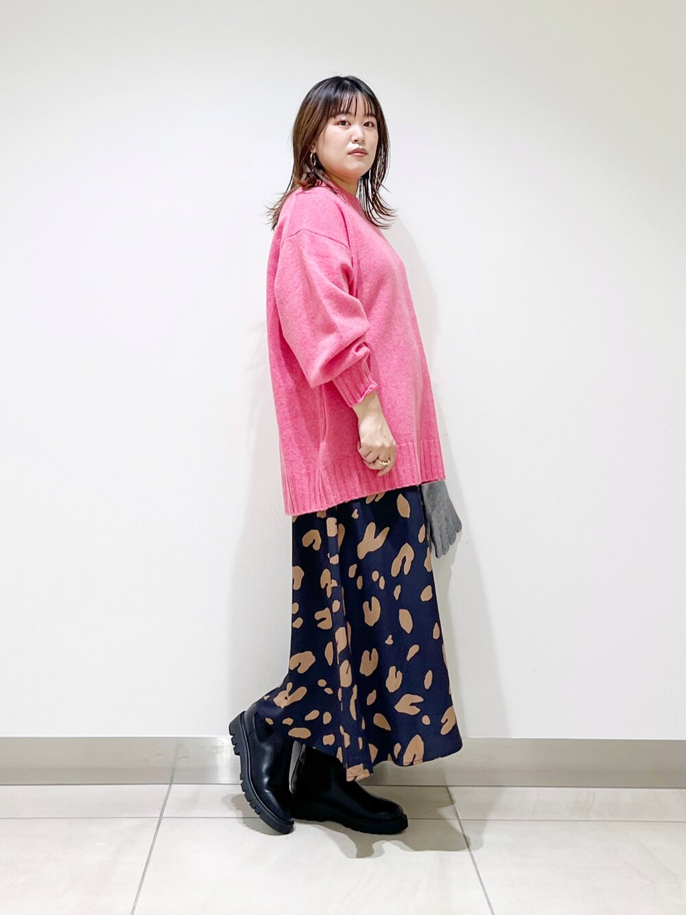 ピンク系のニット/セーター、ブルー系のスカート、ブラック系のブーツを着用したレディースの秋コーディネートの3枚目の写真