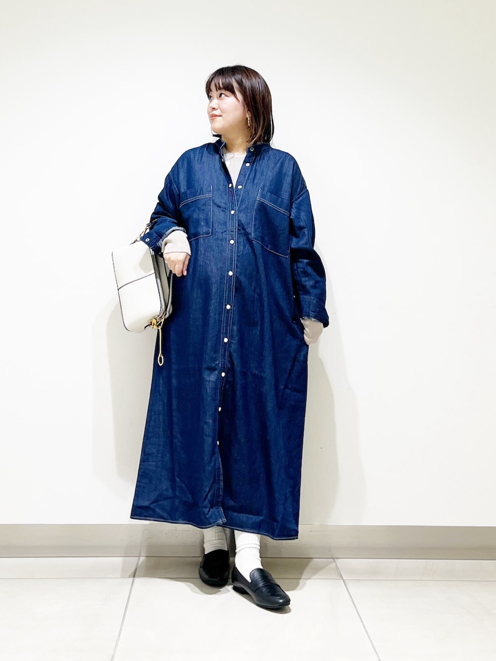 ブルー系のワンピース、ベージュ系のニット/セーター、ホワイト系のショルダーバッグを着用したレディースの秋コーディネートの3枚目の写真