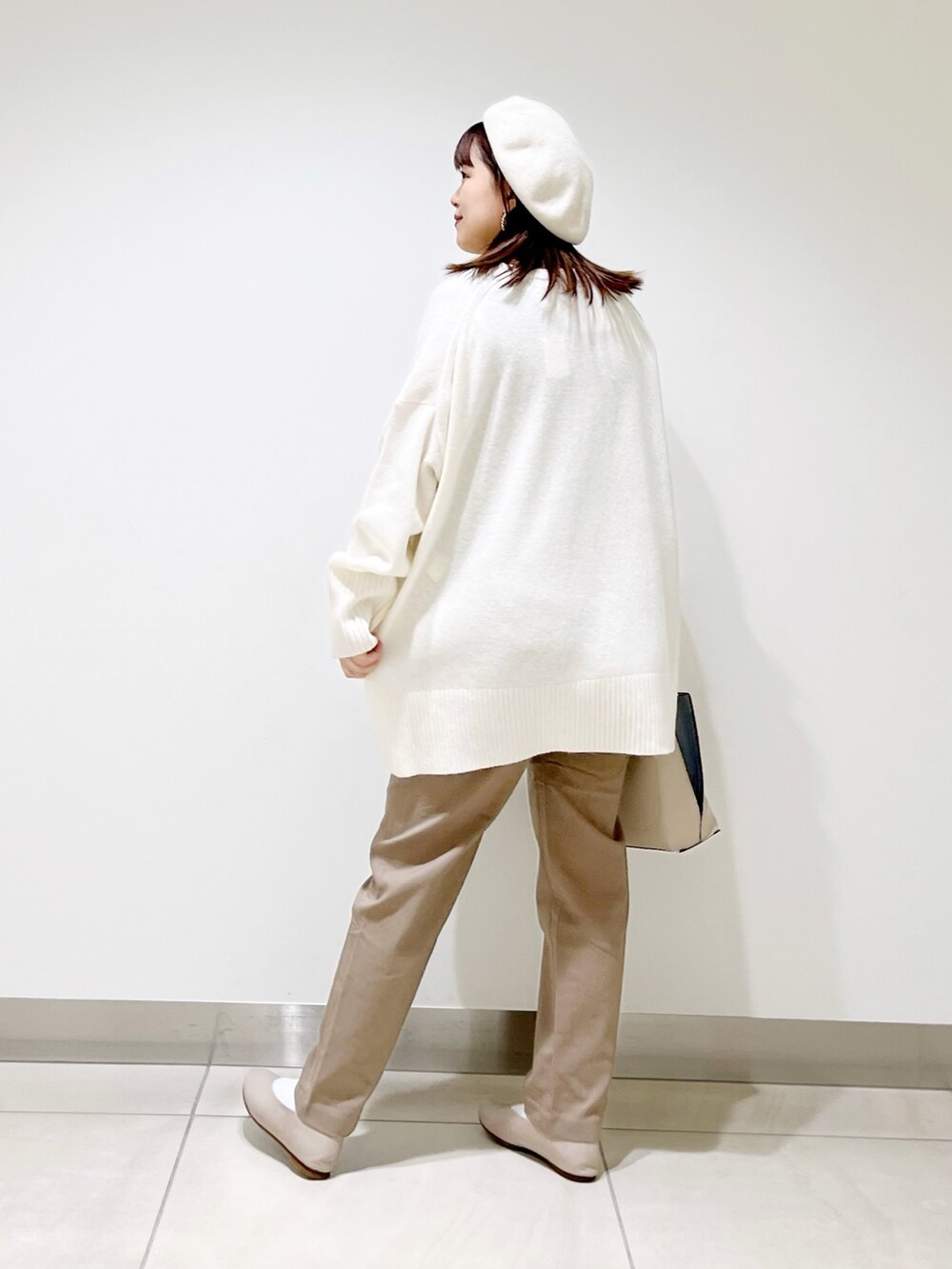 ホワイト系のニット/セーター、ホワイト系のハンドバッグ、ベージュ系のその他パンツを着用したレディースの冬コーディネートの6枚目の写真