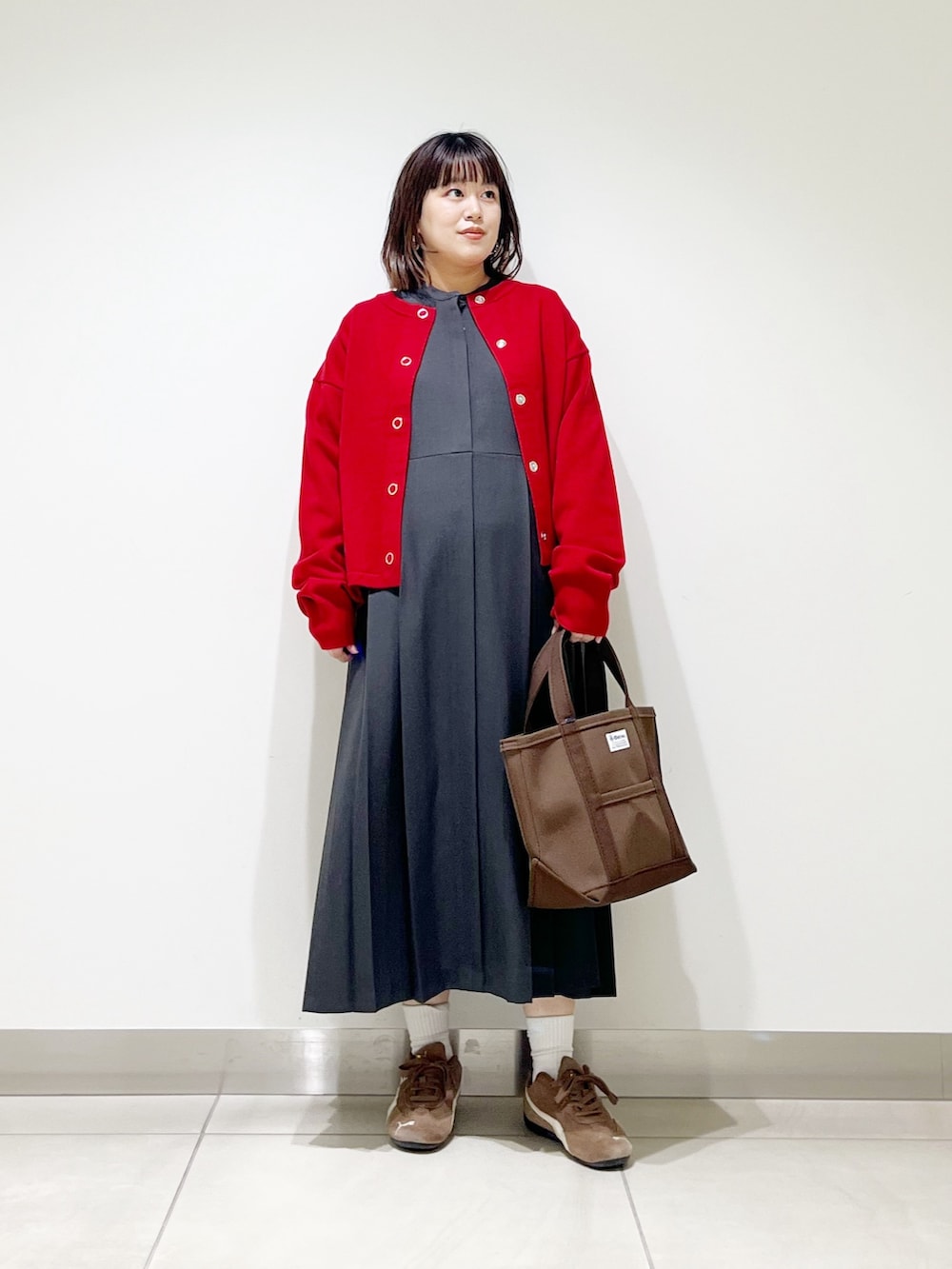 グレー系のワンピース、ブラウン系のトートバッグ、レッド系のカーディガン/ボレロを着用したレディースの秋コーディネートの7枚目の写真