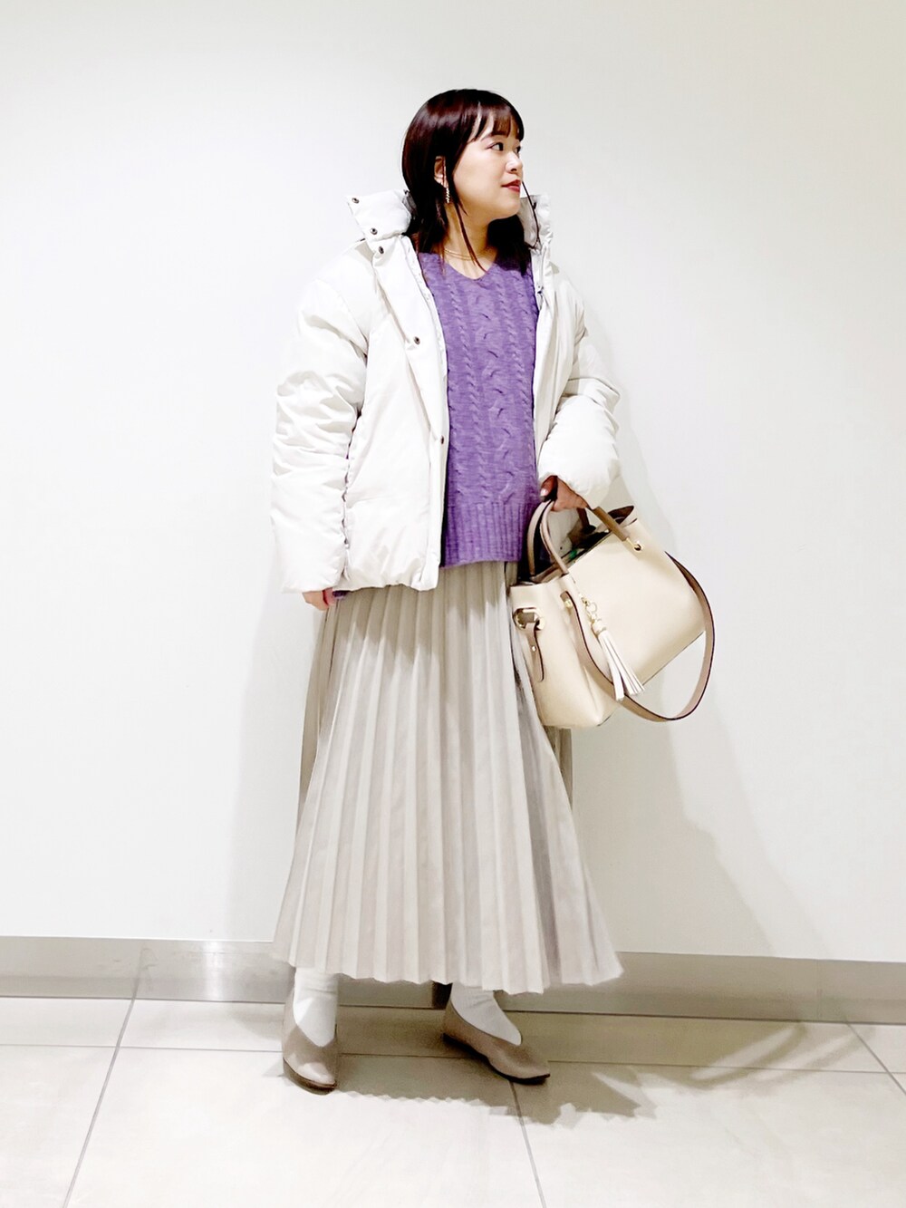 ホワイト系のダウンジャケット/コート、パープル系のニット/セーター、ベージュ系のスカートを着用したレディースの冬コーディネートの5枚目の写真