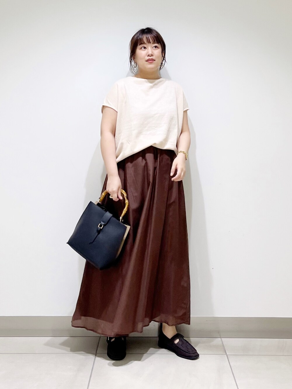 ベージュ系のTシャツ/カットソー、ブラウン系のスカート、ブラック系のハンドバッグを着用したレディースの夏コーディネートの10枚目の写真