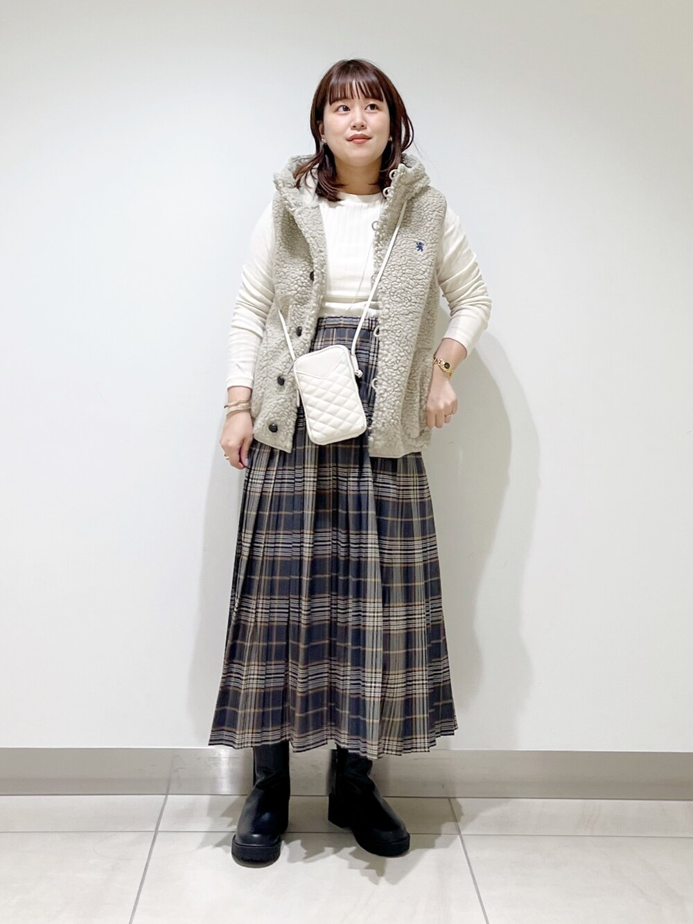 ホワイト系のトップス、グレー系のスカート、ブラック系のブーツを着用したレディースの秋コーディネートの5枚目の写真