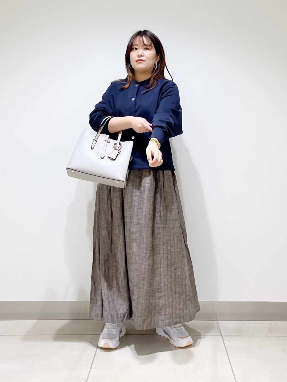 ブルー系のカーディガン/ボレロ、グレー系のトートバッグ、ブラウン系のスカートを着用したレディースの春コーディネートの2枚目の写真