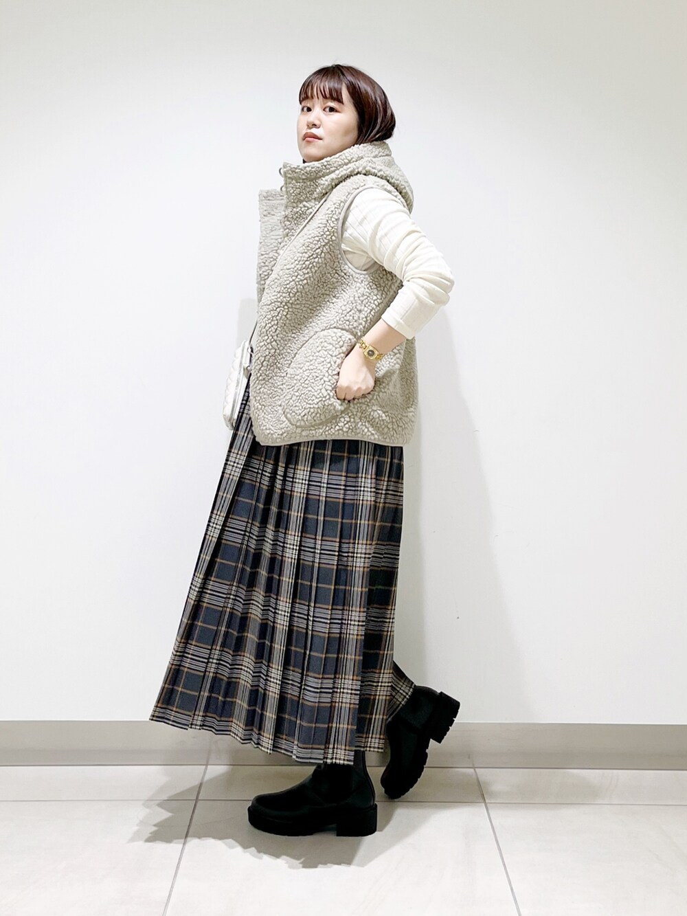 ホワイト系のトップス、グレー系のスカート、ブラック系のブーツを着用したレディースの秋コーディネートの7枚目の写真