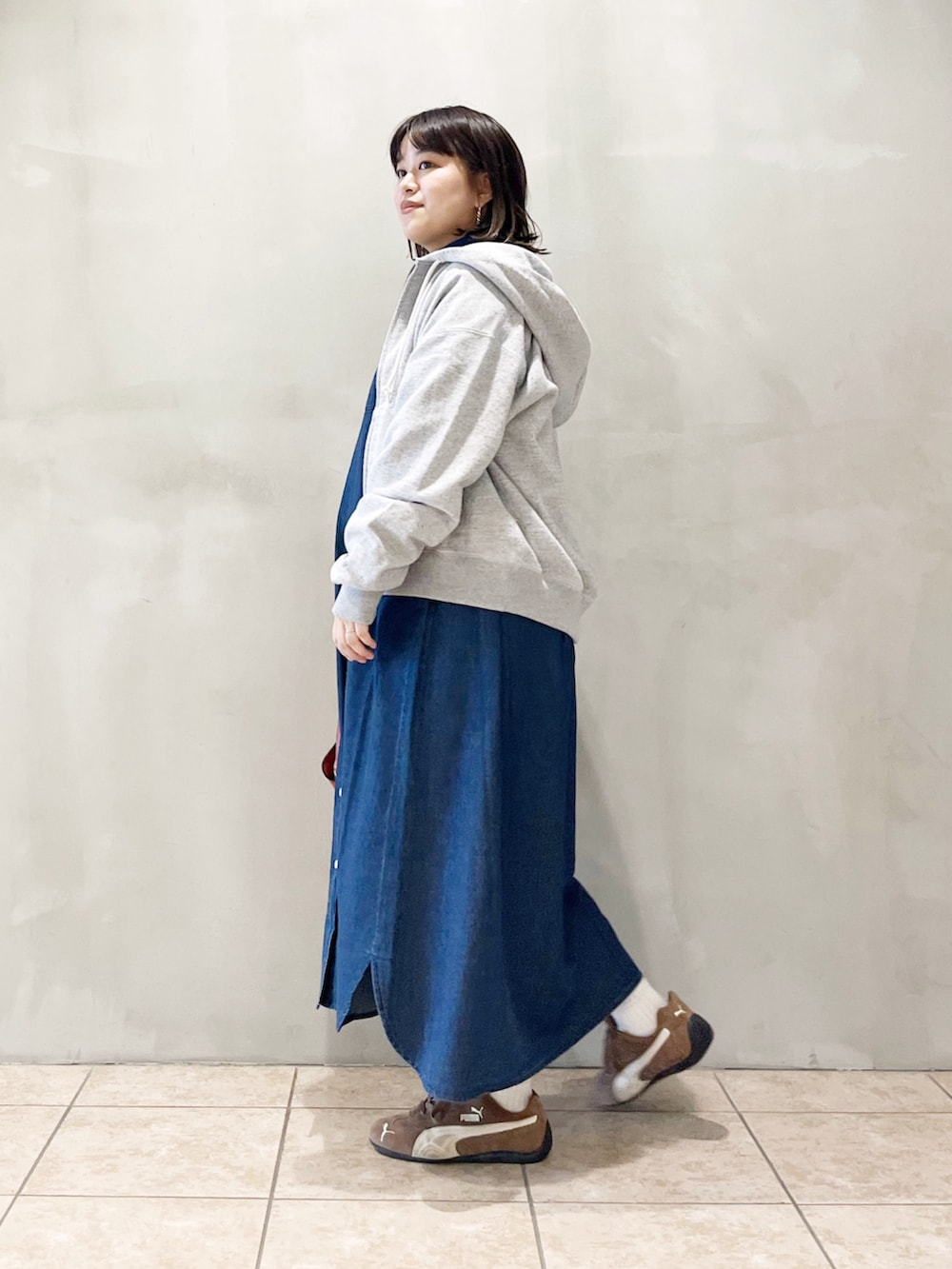 ブルー系のワンピース、オレンジ系のショルダーバッグ、ブラック系のスニーカーを着用したレディースの秋コーディネートの4枚目の写真