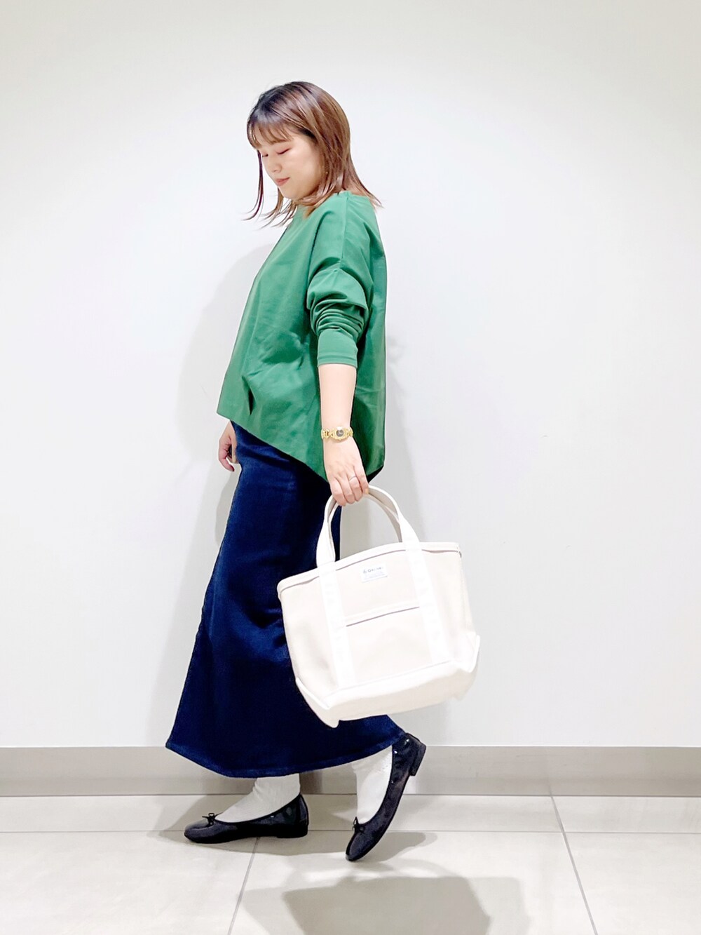 グリーン系のTシャツ/カットソー、ブルー系のスカート、ホワイト系のトートバッグを着用したレディースの秋コーディネートの5枚目の写真