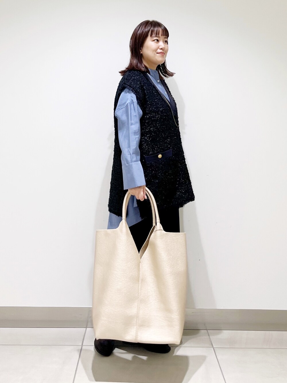 ブルー系のシャツ/ブラウス、ブラック系のスカート、ゴールド系のトートバッグを着用したレディースの秋コーディネートの10枚目の写真